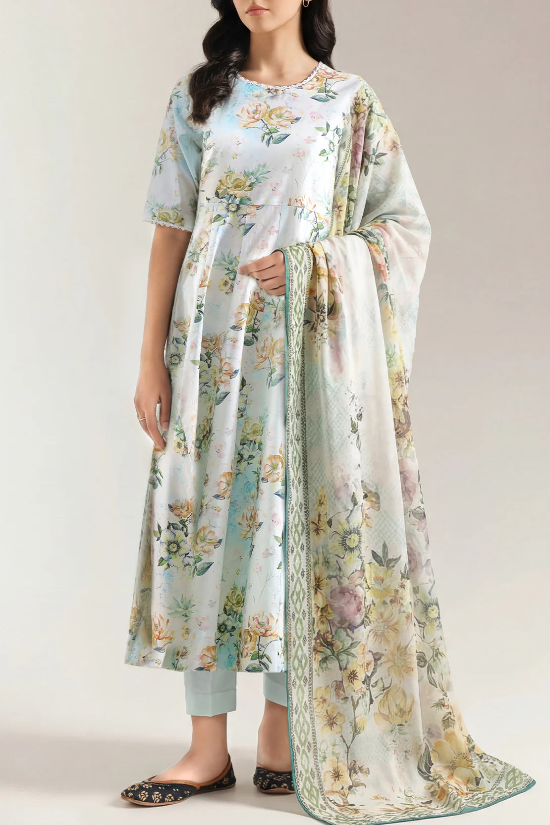 Woman wearing a floral dress with a matching scarf against a white background