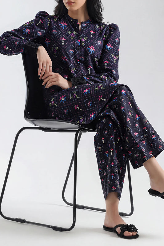 Person wearing a dark floral pajama set sitting on a chair against a white background