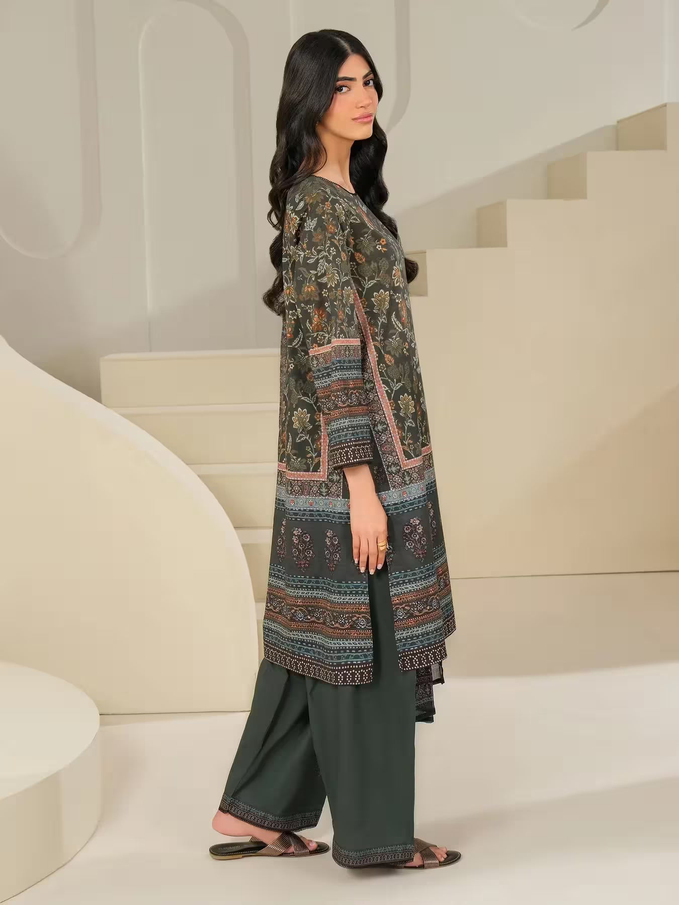 Woman wearing a patterned long shirt and pants in a modern indoor setting