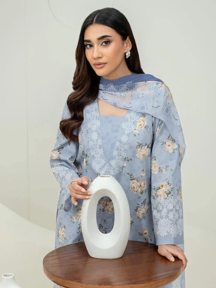 Woman holding a white vase with a light blue floral dress against a plain background