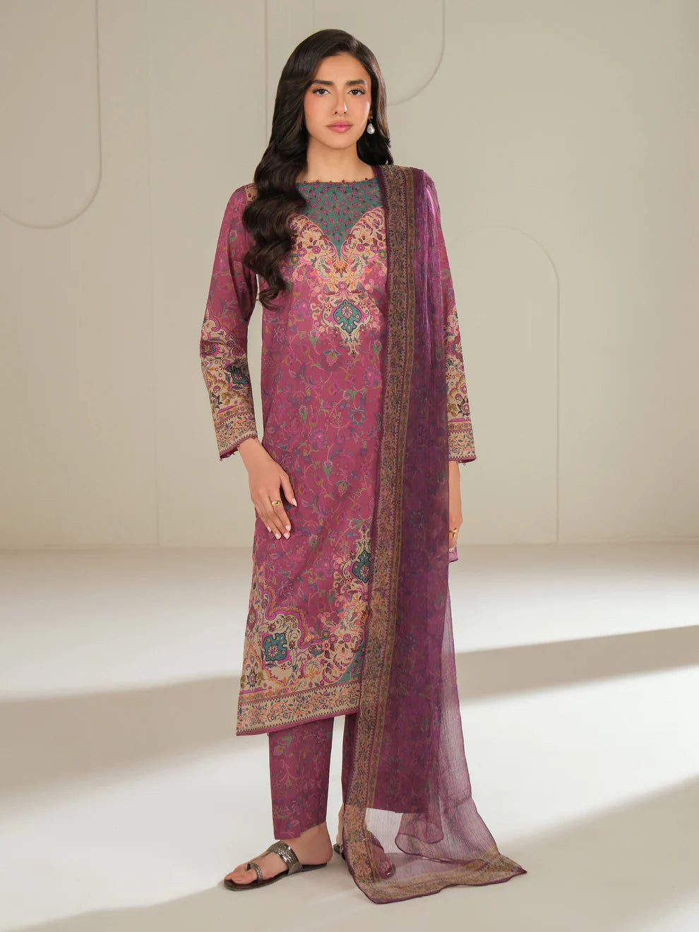 Woman wearing a pink and purple traditional outfit with a matching dupatta on a white background