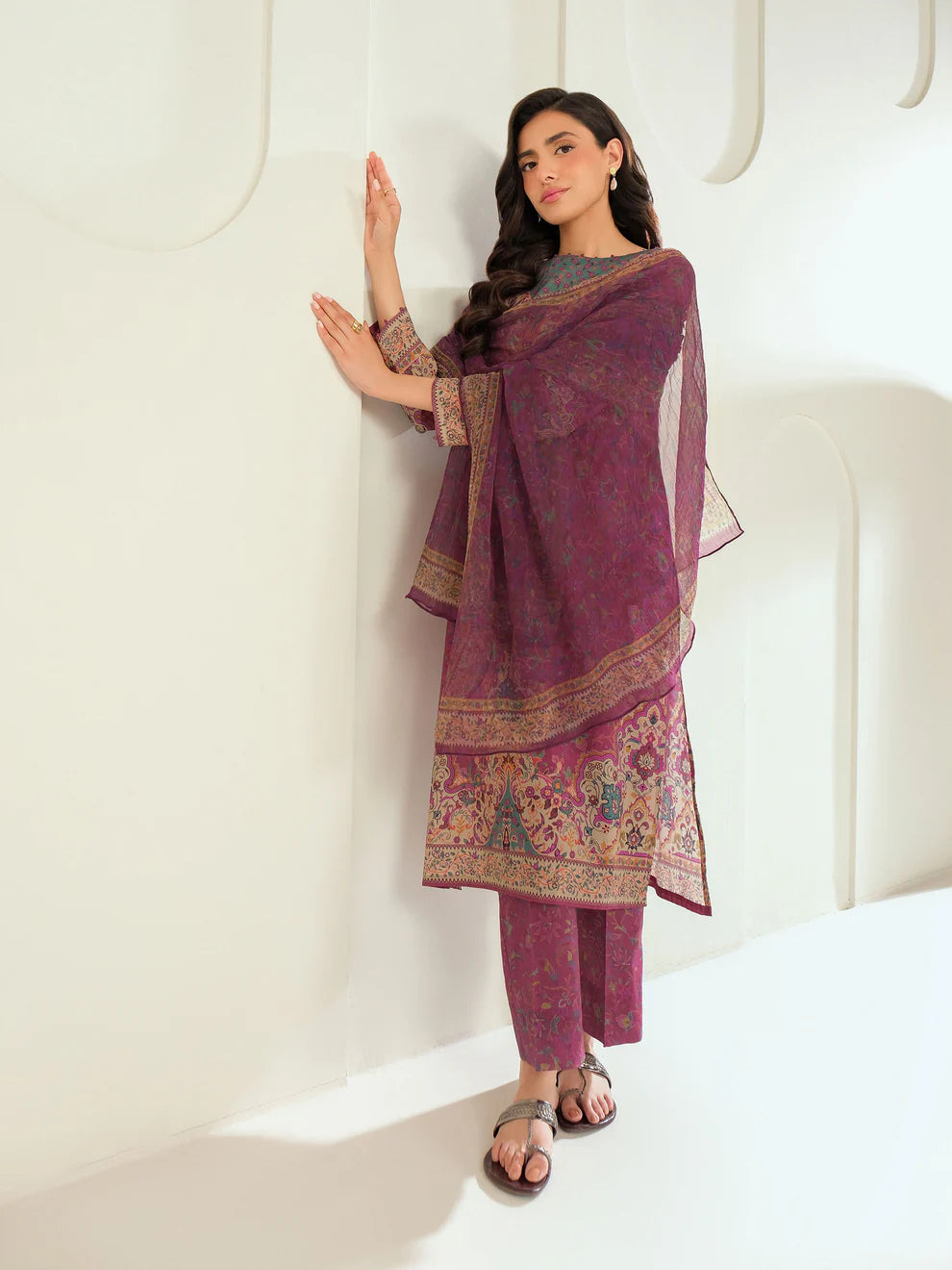 Woman wearing a traditional outfit with a purple dupatta against a white background