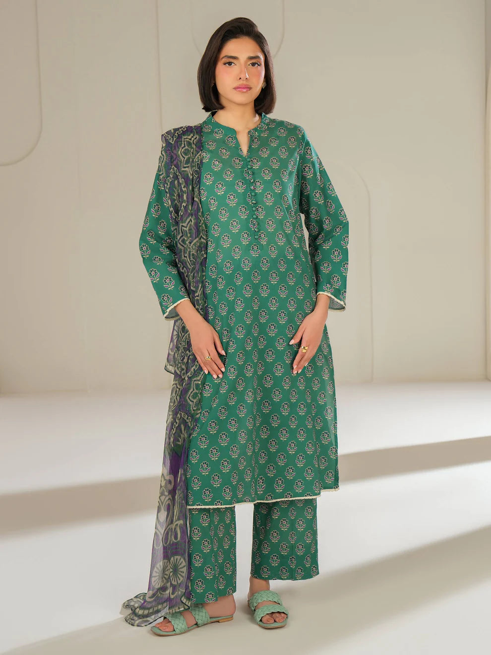 Woman wearing a green traditional outfit with a white background