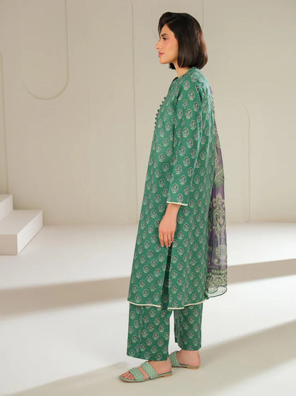 Woman wearing a green traditional outfit with a matching dupatta in a minimalistic setting