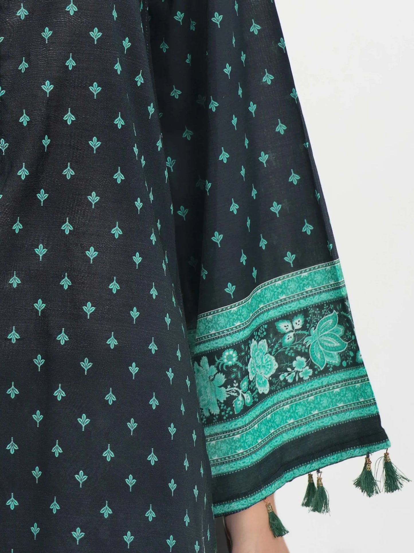Black fabric with green floral patterns and tassels on a white background