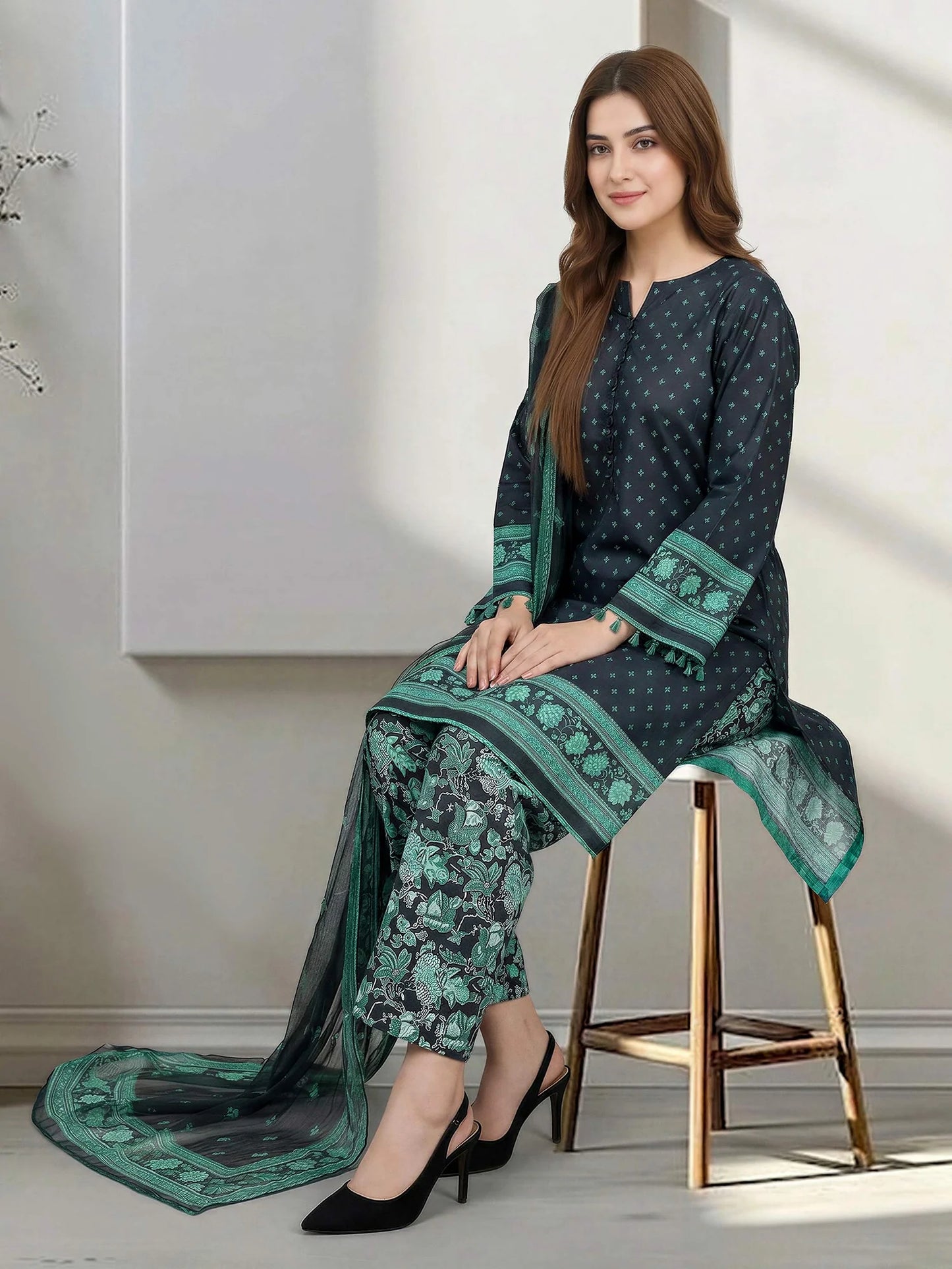 Woman wearing a green and black traditional outfit sitting on a stool.