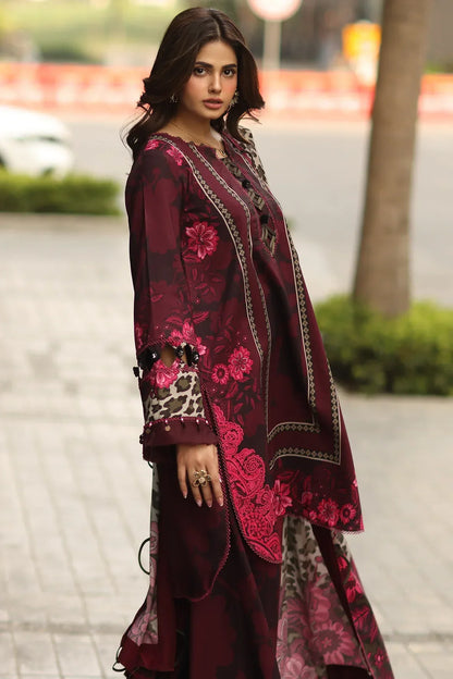 Woman wearing a maroon embroidered traditional outfit with a blurred outdoor background