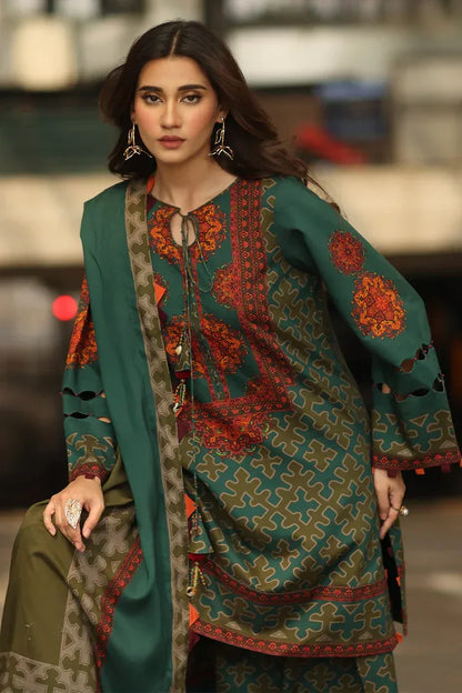 Woman wearing a traditional embroidered outfit with a green dupatta in an urban setting