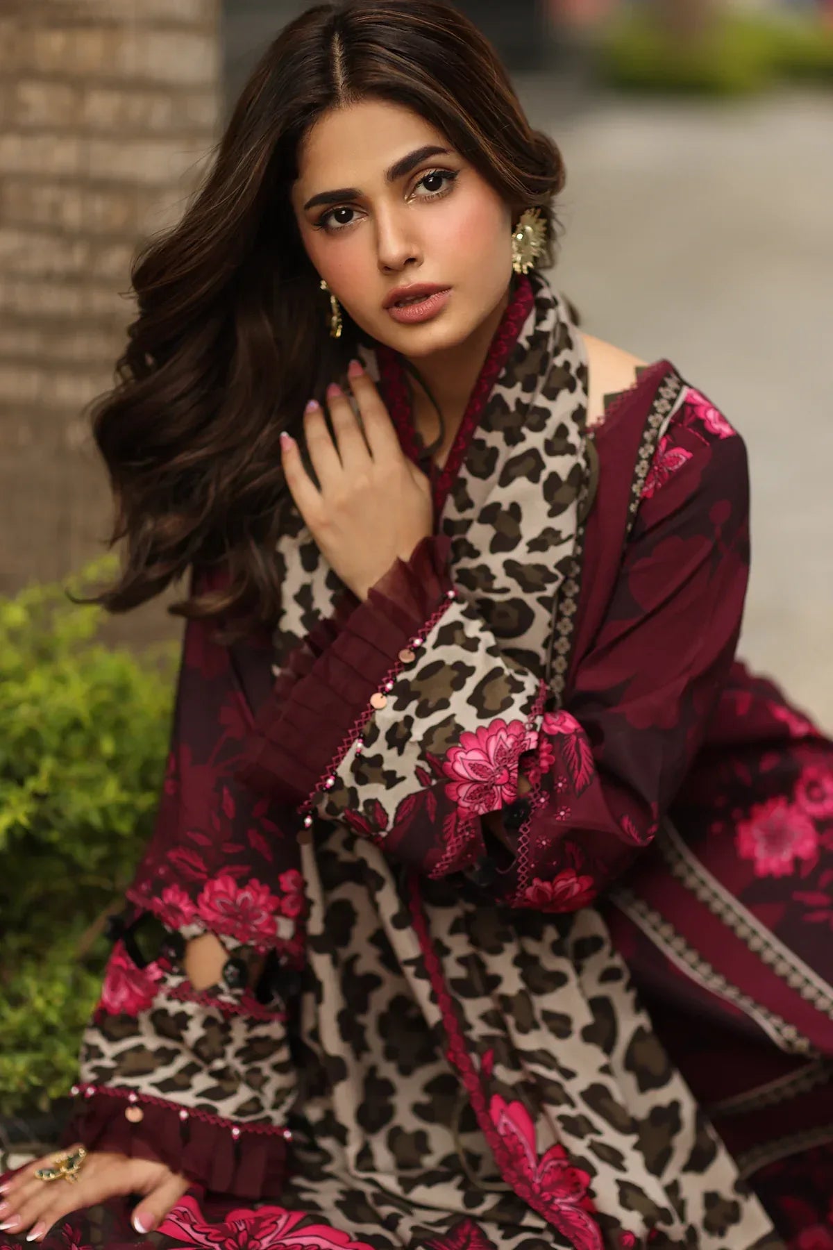 Woman wearing a maroon and white embroidered traditional outfit with a leopard print shawl.