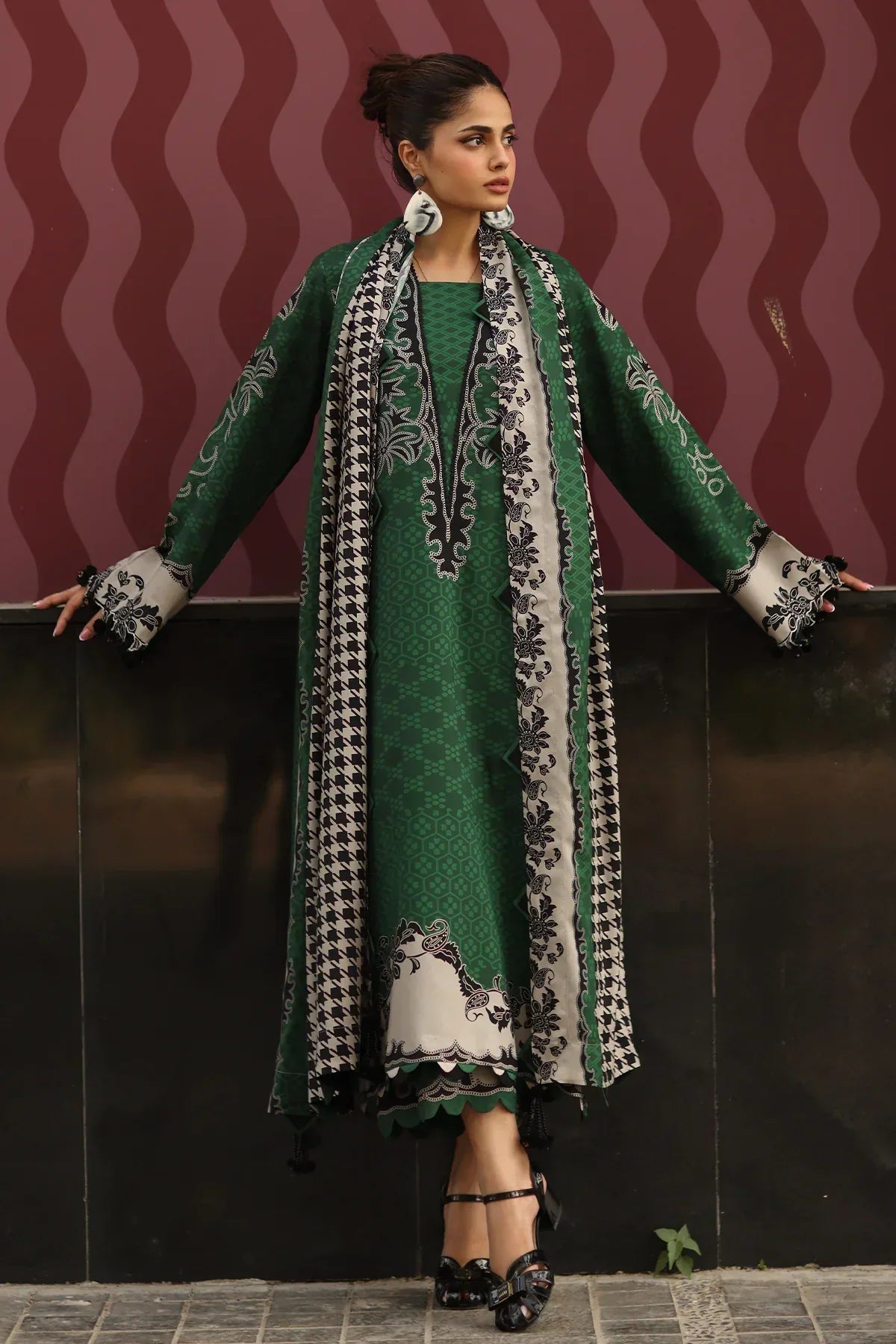 Woman wearing a green traditional outfit with a patterned scarf against a dark background