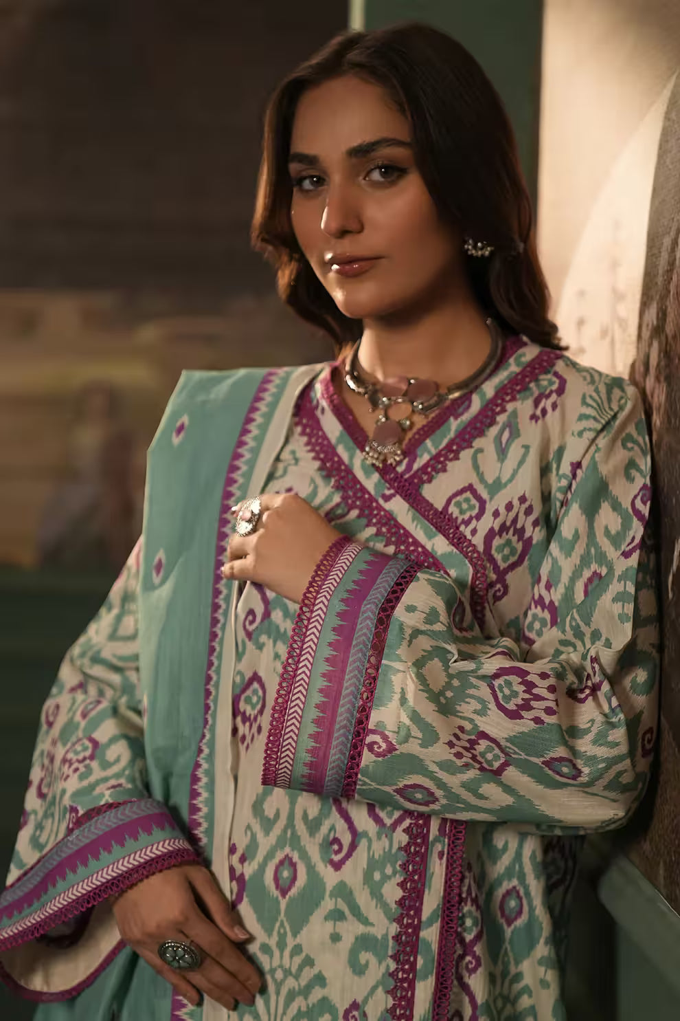 Woman wearing a traditional outfit with intricate patterns in a warm-toned setting