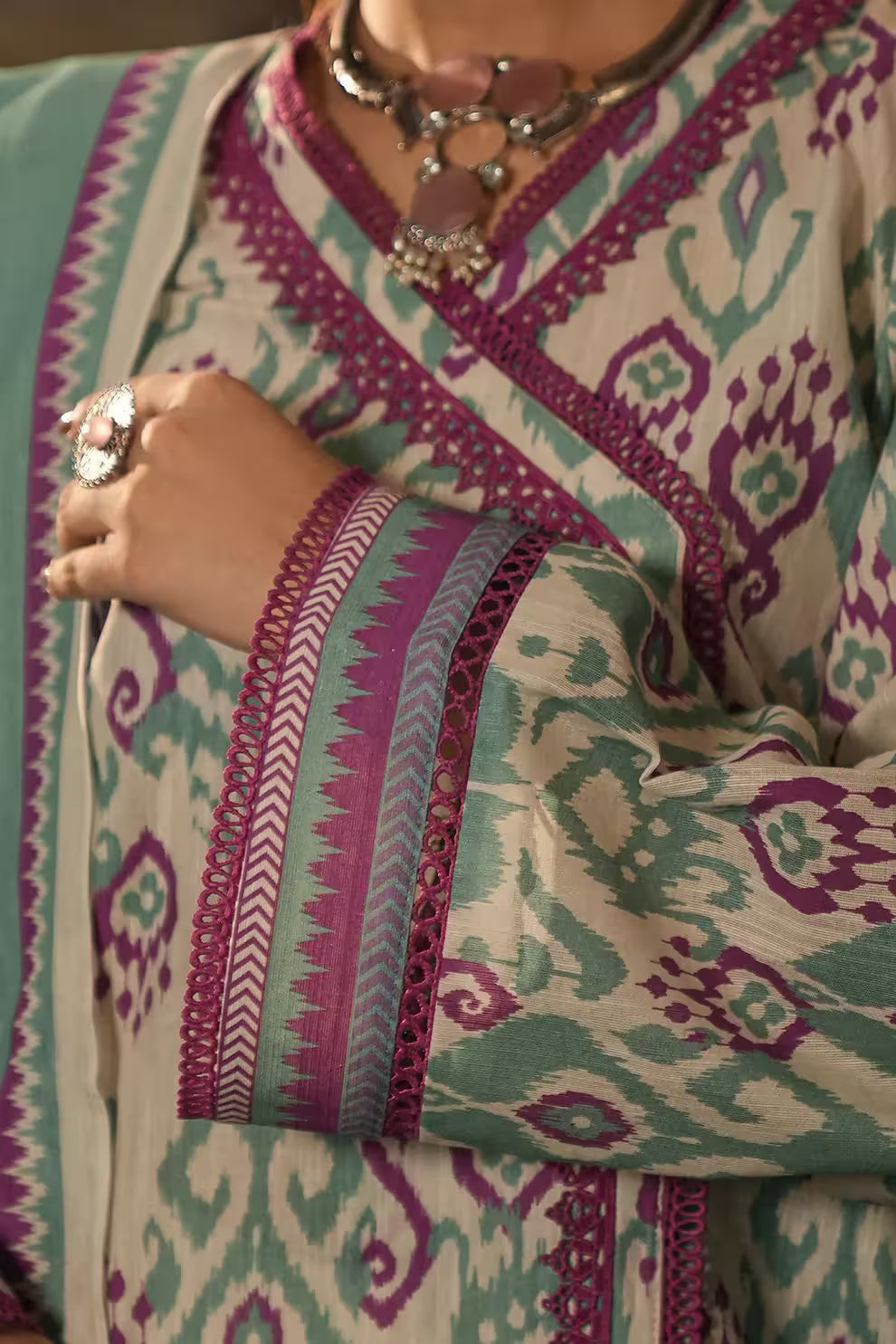 Close-up of a person wearing a patterned garment with intricate designs and jewelry.