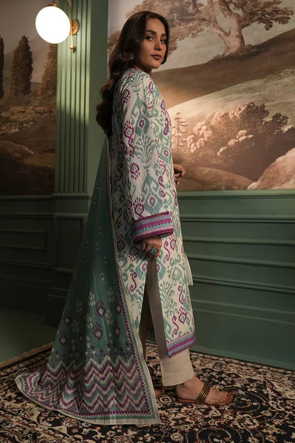 Woman in a patterned outfit standing in a room with a scenic wall painting.