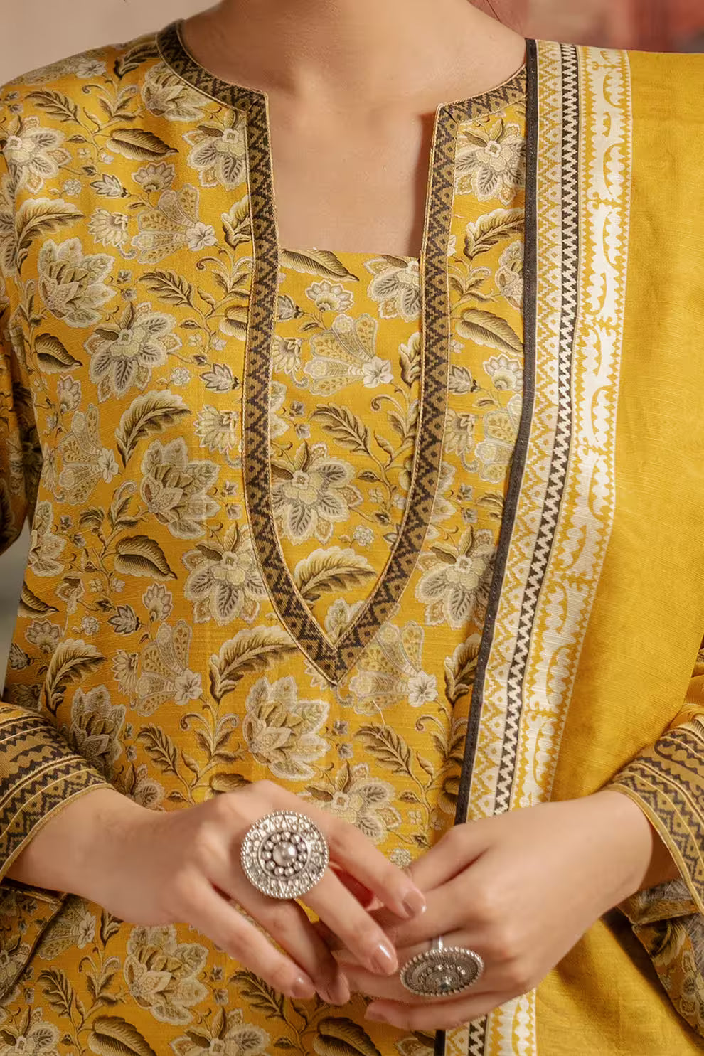 Yellow floral patterned kurta with intricate details on a plain background