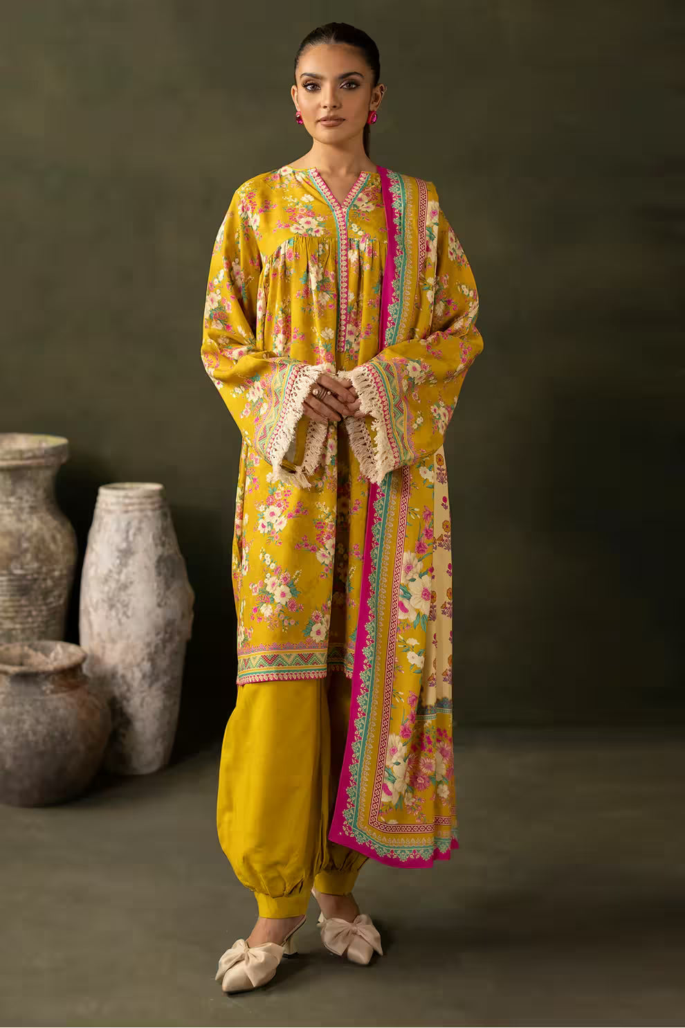 Woman wearing a yellow embroidered traditional outfit with a dark background
