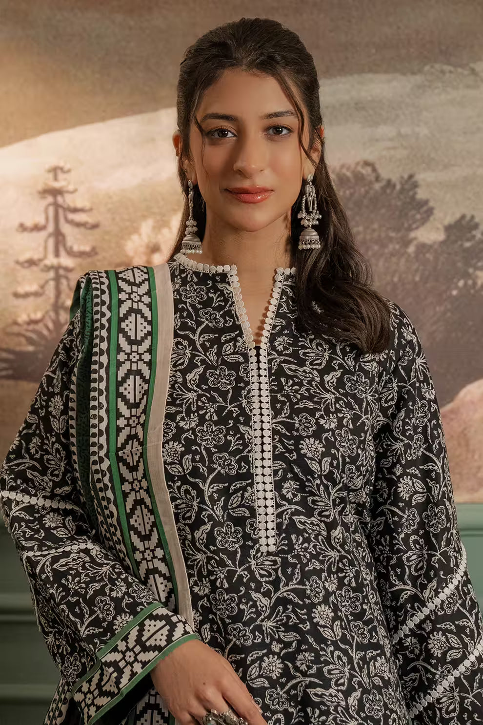 Woman wearing a black and white patterned outfit with green accents against a scenic background