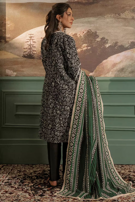 Woman in traditional attire with a patterned shawl against a decorative wall.