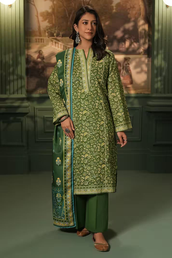 Woman wearing a green traditional outfit with a matching dupatta in a decorated room.