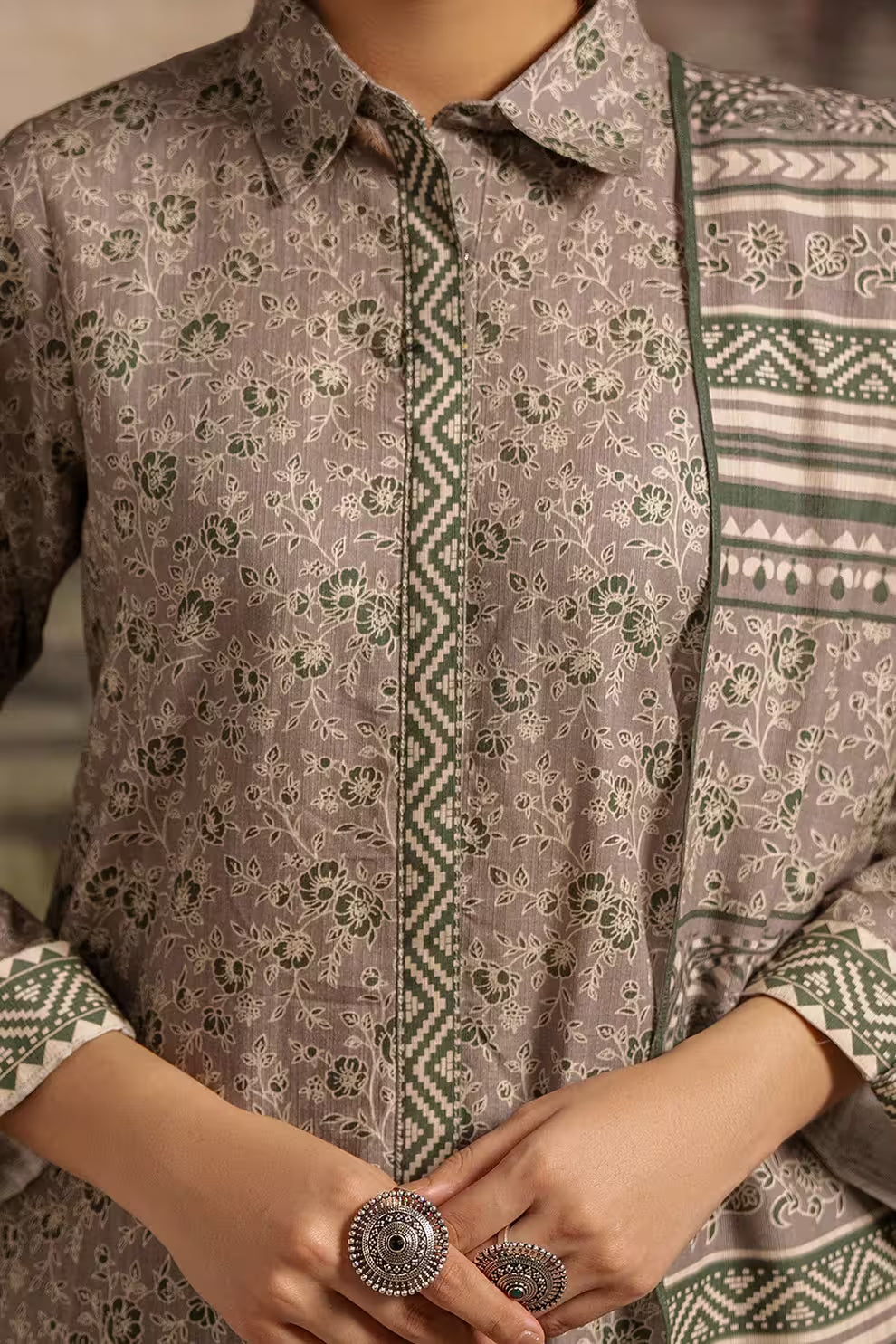 Person wearing a patterned shirt with a focus on the collar and sleeves.