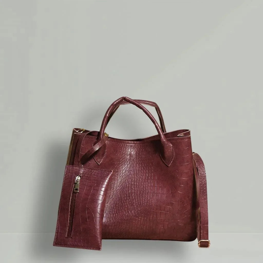 Maroon leather handbag with a shoulder strap on a light gray background