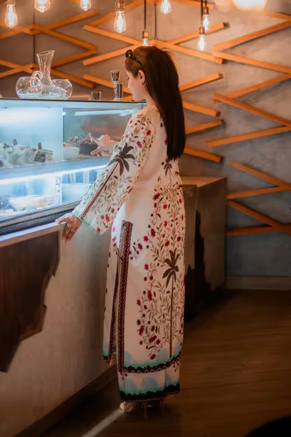 Woman in a floral dress standing by a large aquarium with a geometric wall design.