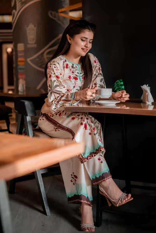 Woman in a floral dress sitting at a table in a restaurant.