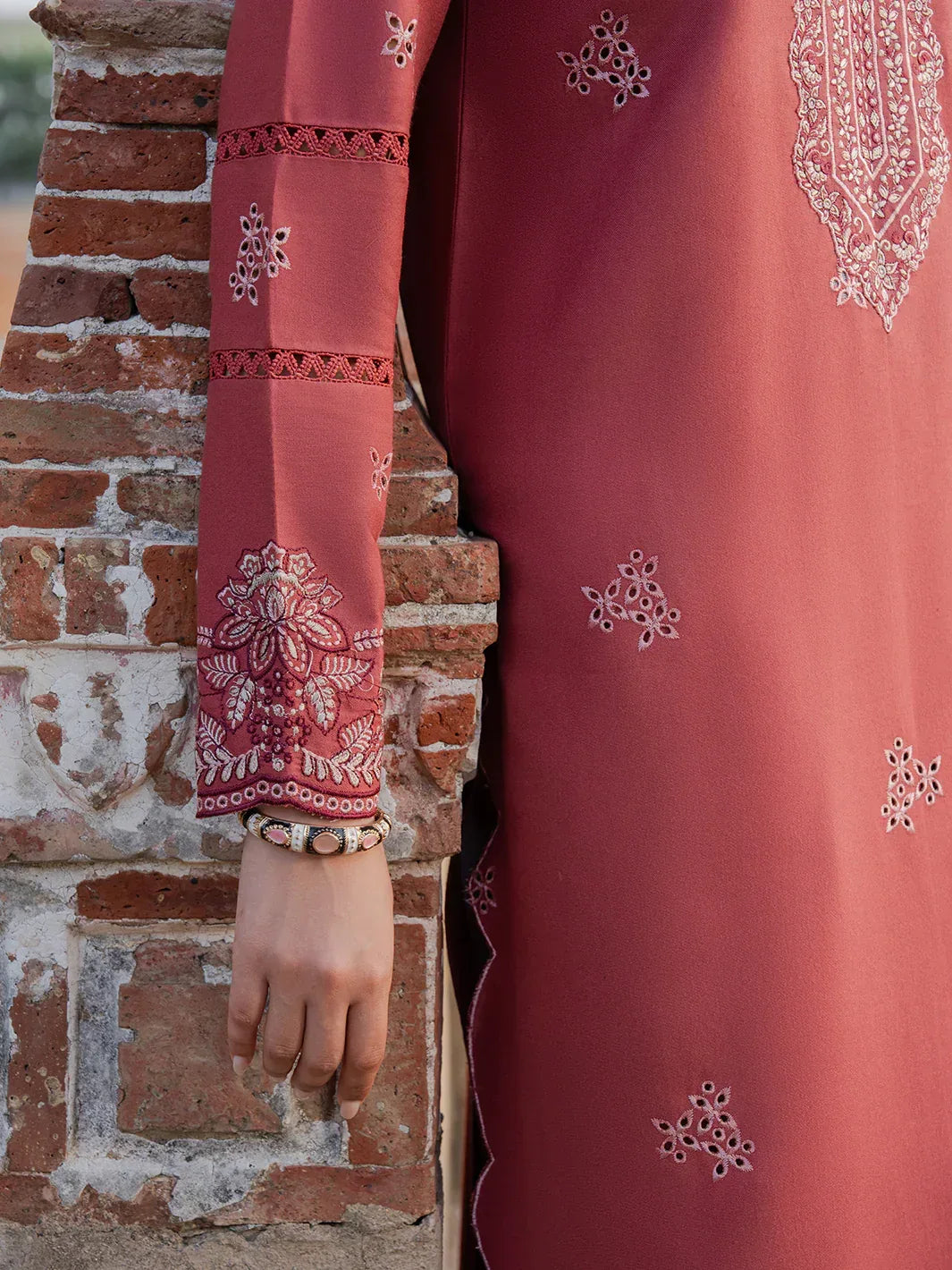 Red embroidered garment against a brick wall