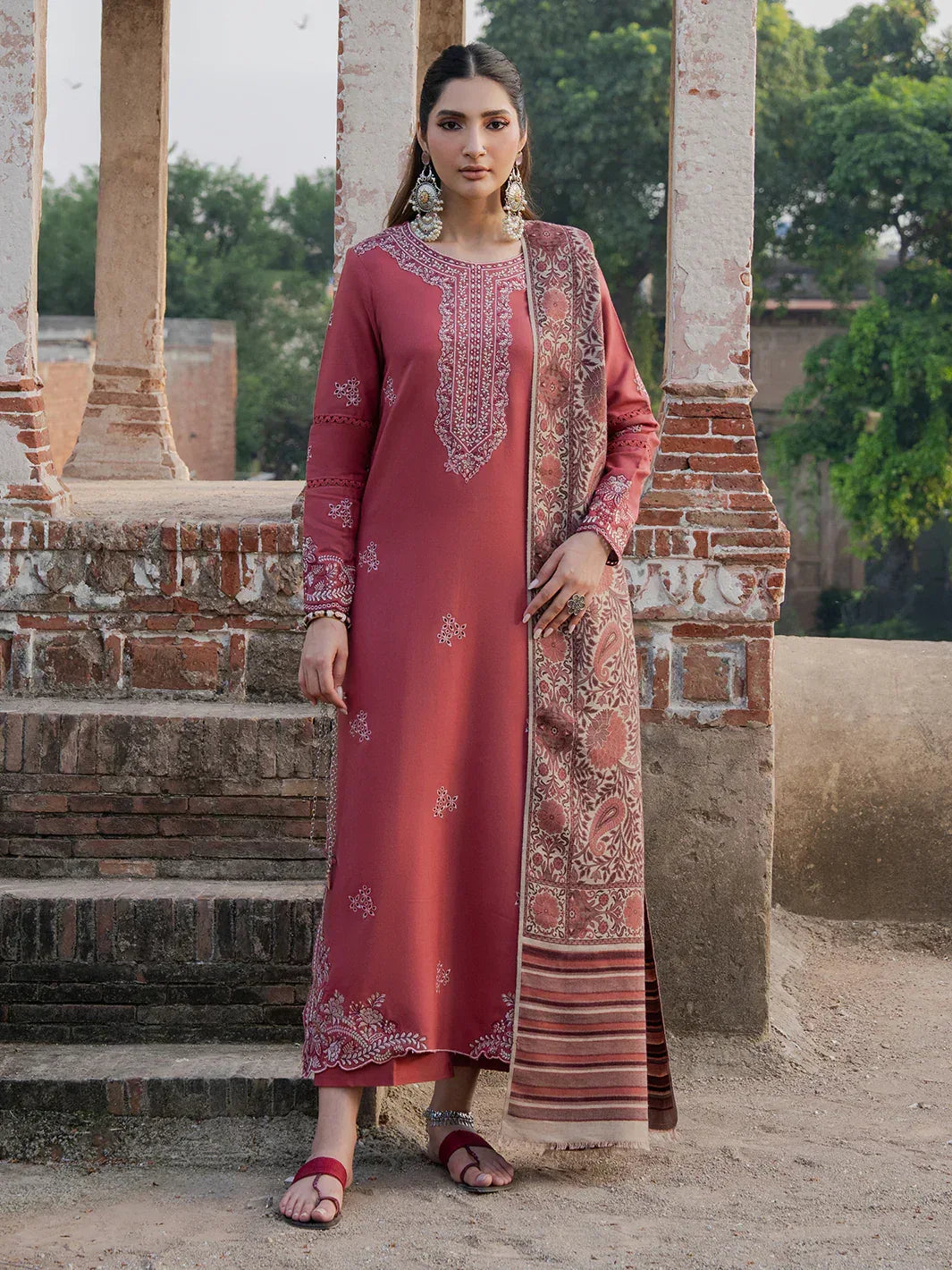 Woman in a traditional outfit standing outdoors with architectural elements in the background