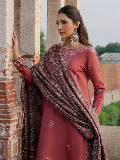 Woman in traditional outfit with embroidered dupatta standing against a historical architecture background