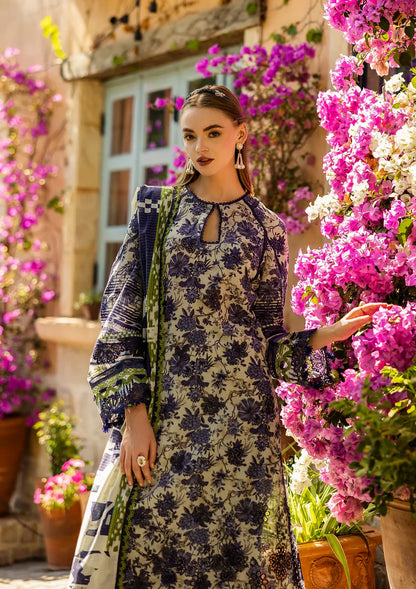 Woman in a floral dress standing among pink flowers with a building in the background