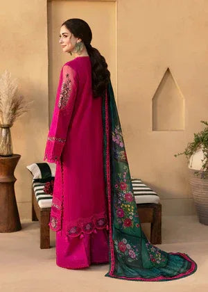 Woman wearing a pink and green embroidered traditional outfit in a room.