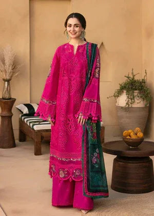 Woman in a bright pink traditional outfit with green accents standing in a room with decorative elements.
