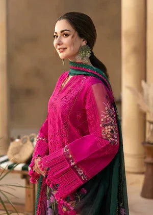Woman in a bright pink and green traditional outfit standing outdoors.