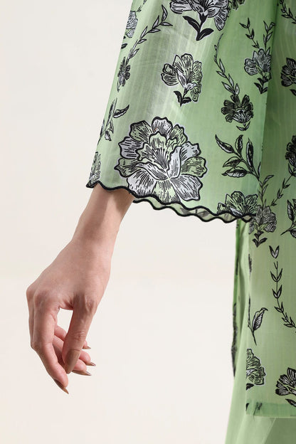 Green dress with black floral patterns on a beige background