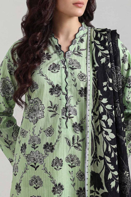 Green floral patterned outfit with a black and white scarf on a neutral background