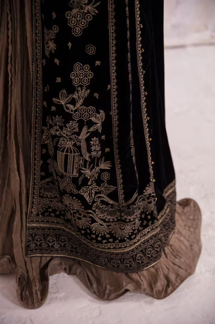 Close-up of a black embroidered garment with gold details on a light background
