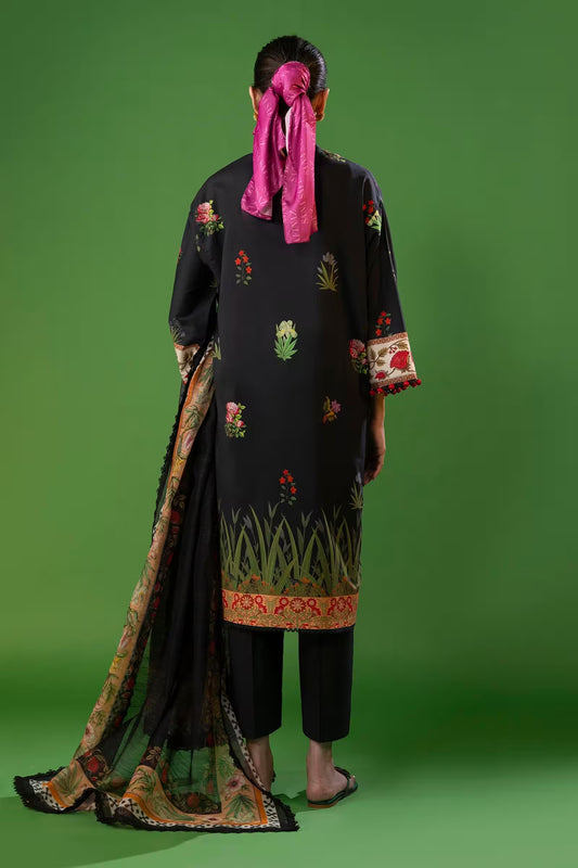 Person wearing a black embroidered outfit with a pink scarf on a green background