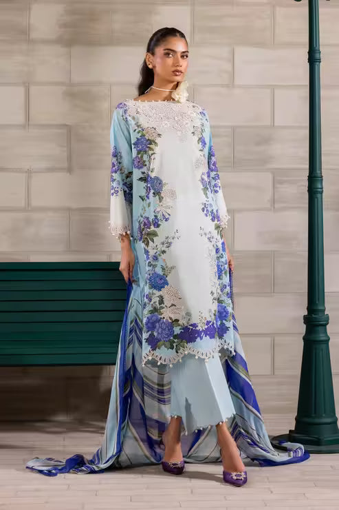Woman wearing a floral dress with a blue and white pattern against a tiled wall.