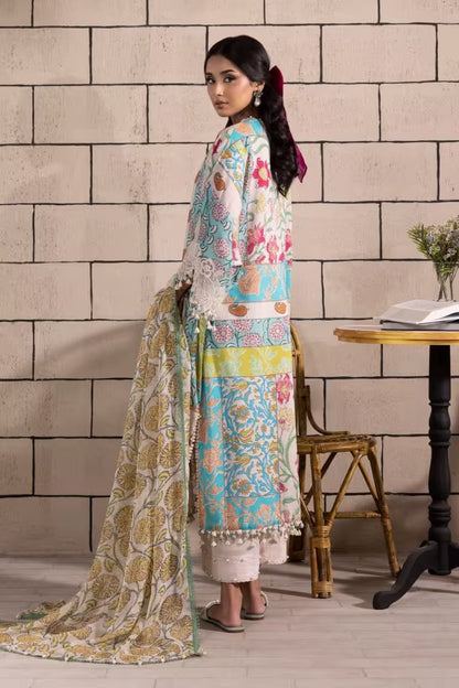 Woman in a colorful traditional outfit standing against a brick wall with a table and chair in the background.