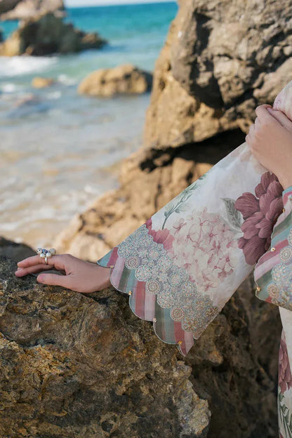 Person wearing a floral dress by the sea with rocks and water in the background