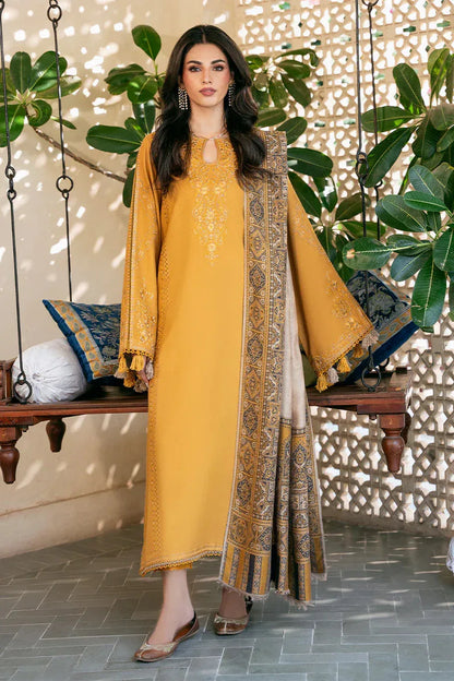Woman in a mustard yellow traditional outfit with a patterned scarf standing in a decorative indoor setting.