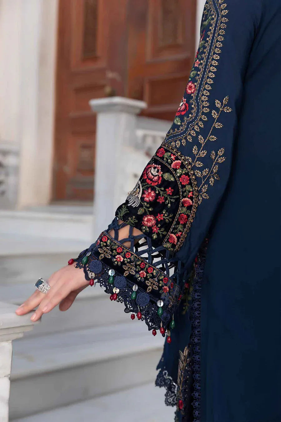 Navy blue embroidered garment with floral patterns on a blurred architectural background