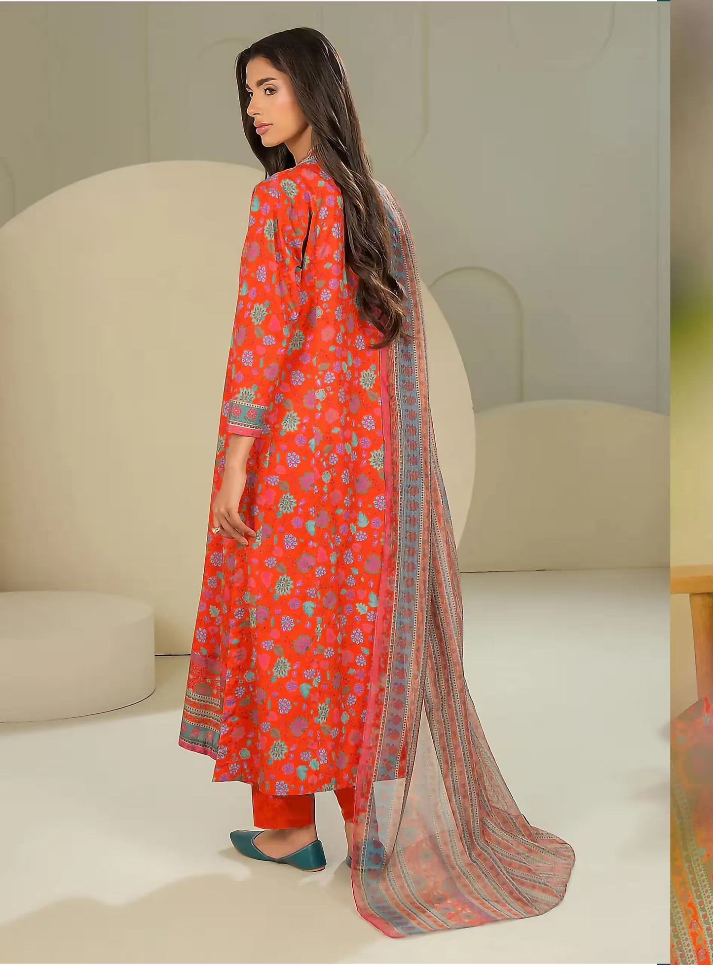 Woman wearing a red traditional outfit with a patterned dupatta in a minimalistic setting