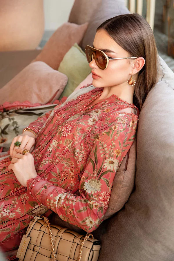 Woman in a floral dress sitting on a couch wearing sunglasses.