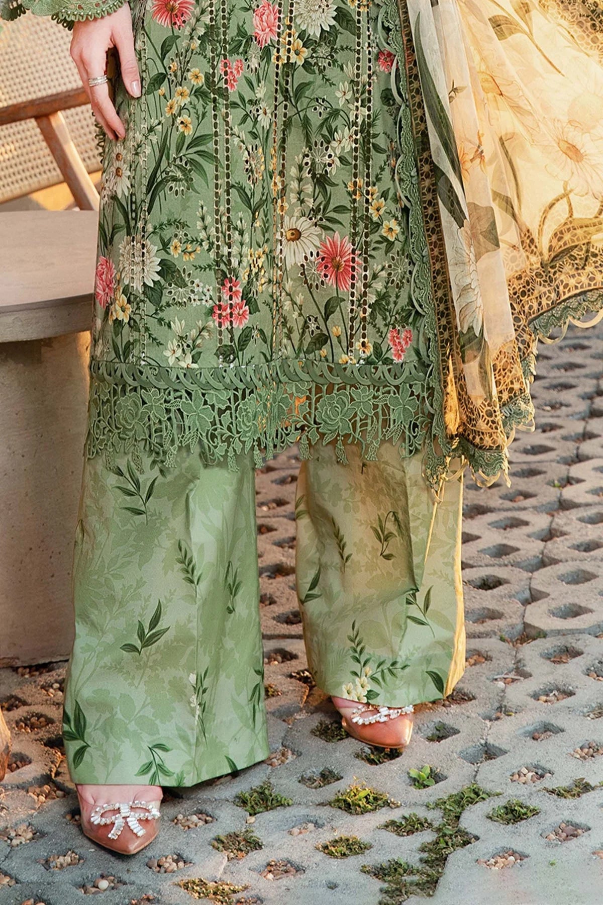 Green embroidered traditional outfit on a textured stone floor.