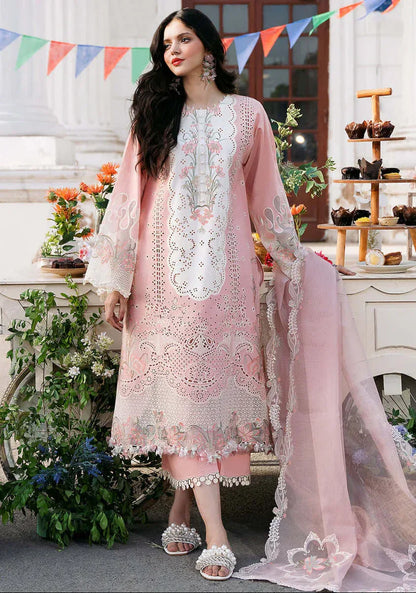 Woman in a pink embroidered outfit standing in an outdoor setting with decorations.
